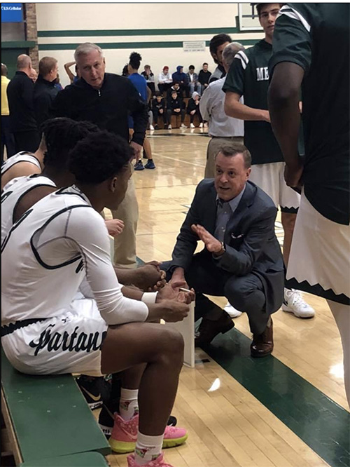 Coach with team on sidelines.